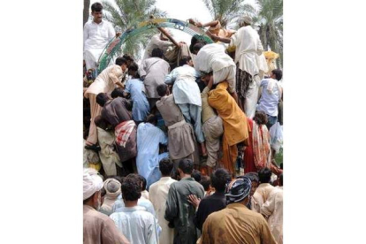 Varios desplazados saquean un camión de distribución de alimentos en Basera, Pakistán.