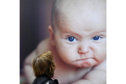 Una mujer pasa ante la fotografía de un bebé en la calle. zennaro
