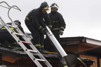 Los bomberos retiran la chimenea de la cubierta afectada por el fuego.