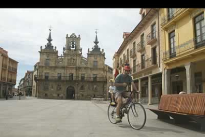Un hombre, acompañado por un niño, atraviesa la Plaza Mayor de Astorga.