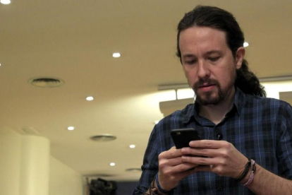 El secretario general de Podemos, Pablo Iglesias, mira su móvil antes de comparecer ante los medios, este jueves.