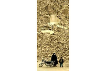 Una mujer iraní y su hijo junto a su moto, en las ruinas de Bam