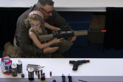 Un hombre muestra a una niña cómo coger una escopeta de aire comprimido durante el NRA Youth Day, en la reunión anual de la NRA, en Houston, en el 2013.