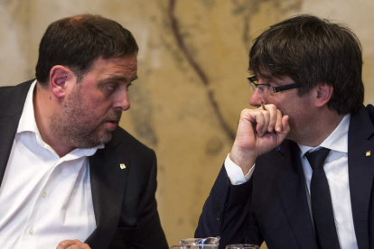 El consejero de Economía, Junqueras, conversa con el presidente Puigdemont. QUIQUE GARCÍA