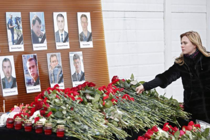 Una mujer deja flores ante los retratos de los periodistas muertos en el accidente. SERGEI ILNITSKY