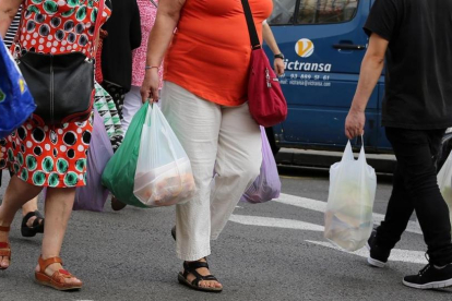 Consumidores con bolsas de plástico de asas