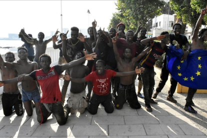 Un grupo de los inmigrantes que ayer saltaron la valla en Ceuta posan con una bandera de la UE.