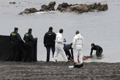 Agentes de la Guardia Civil retiran el cuerpo del subsahariano encontrado hoy en la playa del Tarajal de Ceuta.