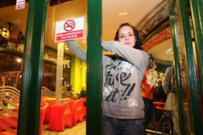 Una trabajadora coloca el cartel de prohibido fumar por la Ley Antitabaco.