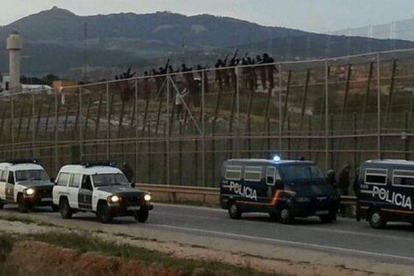 Algunos de los subsaharianos, encaramados en lo alto de la valla de Melilla, este viernes.