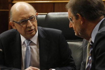 El ministro de Hacienda, Cristóbal Montoro, conversa con el presidente del Gobierno, Mariano Rajoy, este martes durante el debate sobre los Presupuestos en el Congreso.