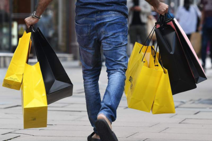 Un hombre carga con bolsas tras realizar sus compras. ANDY RAIN