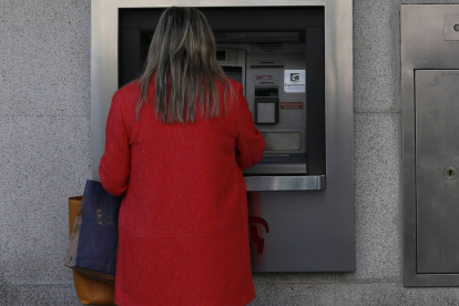 Una mujer saca dinero de un cajero automático en León. ARCHIVO