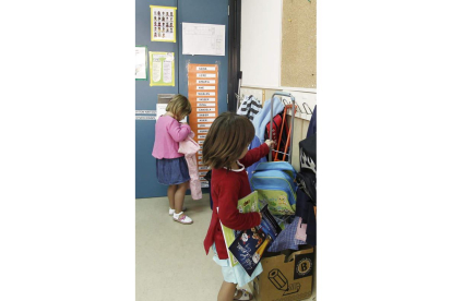 Dos niñas colocan sus mochilas al llegar a clase.