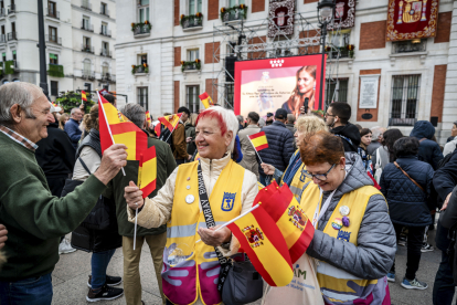 Varias mujeres reparten banderas de España frente a la Real Casa de Correos, sede del Gobierno de la Comunidad de Madrid, donde decenas de personas comienzan a congregarse. FERNANDO VILLAR
