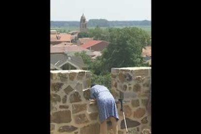 Una vecina se asoma a lo alto de un muro para ver la procesión.