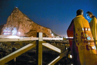 Una pareja mira desde la Línea de la Concepción la proyección de la imagen de Isabel II en el Peñón, en junio del 2012, cuando las autoridades de Gibraltar celebraron el 60º aniversario del ascenso al trono de la reina.