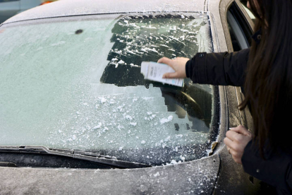Una persona rasca el hielo del parabrisas de su coche. RAQUEL MANZANARES