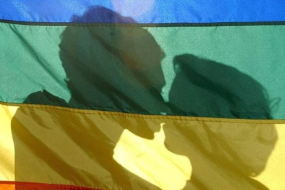 Una pareja velada por la bandera arcoíris en un acto del día del Orgullo LGTBIQ+. JESUS F. SALVADORES