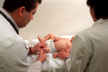 Dos sanitarios vacunan a un bebé en un ambulatorio.