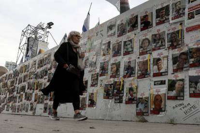 Una mujer israelí pasa junto a un muro con imágenes.