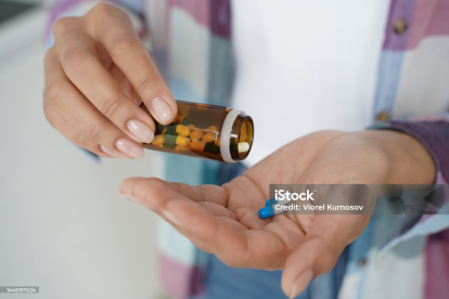Una mujer con un frasco de pastillas para un tratamiento.