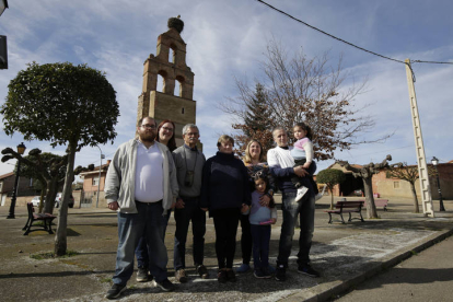 Las tres nuevas familas que han llegado al Órbigo desde Barcelona con sus ocho miembros, delante del campanario de Palazuelo.