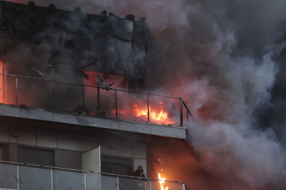 Bomberos trabajan en el incendio declarado sobre las cinco y media de esta tarde en un quinto piso de un edificio de viviendas de Valencia.