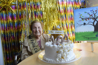 Ángeles Crespo con su tarta de cumpleaños y el árbol con las huellas de sus compañeros y compañeras.