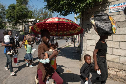 Habitantes caminan por una calle este sábado en Puerto Príncipe (Haití). Presuntos delincuentes fueron abatidos por la Policía Nacional de Haití durante un ataque al Palacio Nacional la noche del viernes en Puerto Príncipe, orquestado por la coalición de bandas armadas "Vivre Ensemble", según publicaron este sábado medios locales. EFE/ Johnson Sabin