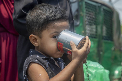 Un niño bebe agua en un tanque junto a una carretera en Dhaka (Bangladesh).