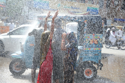 Un grupo de personas disfruta de una ducha de agua fría rociada por un camión de emergencias, a medida que aumentan las temperaturas en Pakistán este martes. EFE/ Shahzaib Akber
