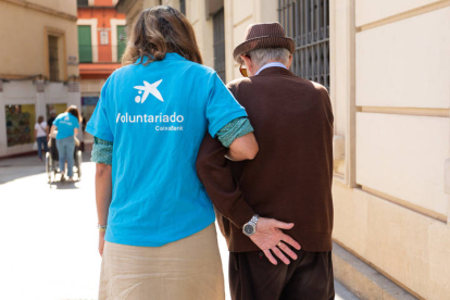 Una voluntaria acompaña a un anciano.