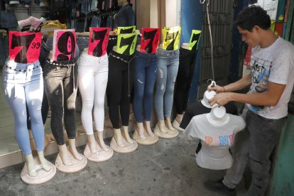 Un vendedor organiza productos en una tienda de ropa, este miércoles en el centro de San Salvador (El Salvador). EFE/Rodrigo Sura