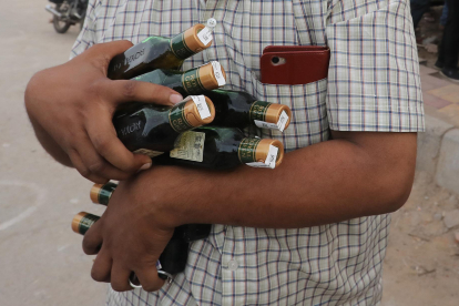 Imagen de archivo de un ciudadano indio con varias botellas de alcohol en Nueva Delhi. EFE/EPA/RAJAT GUPTA