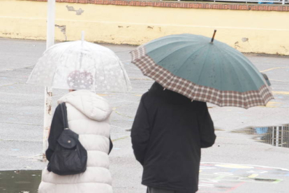 Dos personas se protegen de la lluvia con paraguas.