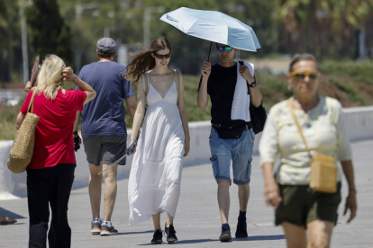 Una pareja utiliza una sobrilla para protegerse del sol este miércoles cuando el calor sofocante comienza a apretar y pone en alerta a ocho comunidades, con mayor incidencia en Castilla-La Mancha y en la Región de Murcia.