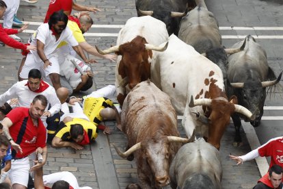 Los mozos son perseguidos por los toros de la ganadería abulense de José Escolar Gil durante el séptimo encierro de los Sanfermines 2024 este sábado en Pamplona. EFE/Villar López