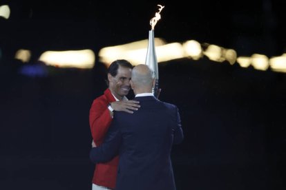 El tenista español Rafa Nadal (i) recoge la antorcha olímpica de manos del exfutbolista Zinedine Zidane en la Plaza del Trocadero.