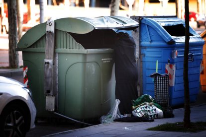 Una persona busca en un contenedor de basura