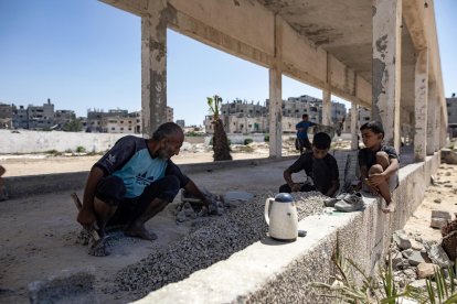 El palestino desplazado Maysara Omar y sus hijos rompen piedras recogidas de casas destruidas por ataques aéreos israelíes anteriores, para venderlas para hacer lápidas, en Khan Younis, sur de la Franja de Gaza, el 21 de agosto de 2024. 
                       EFE/EPA/HAITHAM IMAD