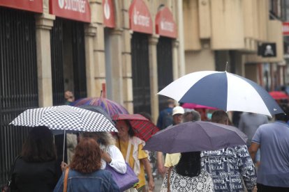 Varias personas se protegen de la lluvia en Ordoño.