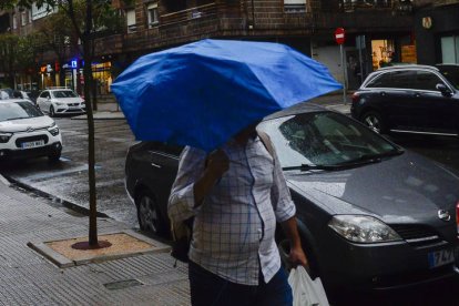 Un hombre pasea por León en un día de lluvia y viento