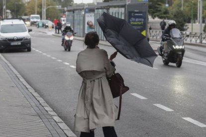 Una mujer lucha contra el viento que le ha dado la vuelta a su paraguas este miércoles en Madrid.