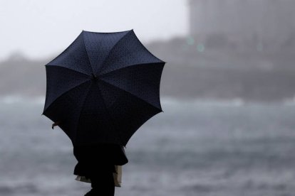 Una mujer lucha contra el viento que le ha dado la vuelta a su paraguas este miércoles en Madrid.