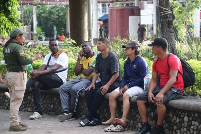 Personal del Instituto Nacional de Migración (INM) habla con migrantes en una plaza pública este sábado, en Tapachula (México). EFE/ Juan Manuel Blanco