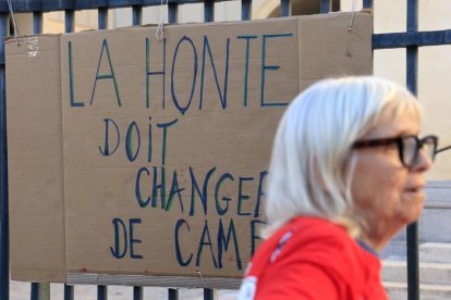 Una mujer pasa junto a un cartel en apoyo a Giséle Pelicot en Montpellier, Francia.