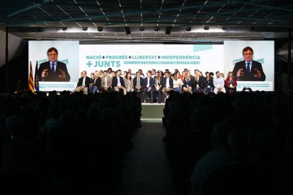 El secretario general de Junts, Jordi Turull (c), escucha la intervención de Carles Puigdemont (en las pantallas) durante el Congreso del partido que se celebra este fin de semana en Calella (Barcelona). EFE/ Quique García