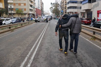 Dos personas abandonan el barrio de La Torre de Valencia, uno de los barrios periféricos de la zona sur que sufre inundaciones a causa de las fuertes lluvias.