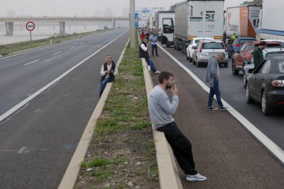 Varios conductores aguardan junto a sus vehículos en la V-30 junto al nuevo cauce del Turia durante la mañana de este miércoles en la que la red principal de carreteras de Valencia continúa cortada en varios puntos.